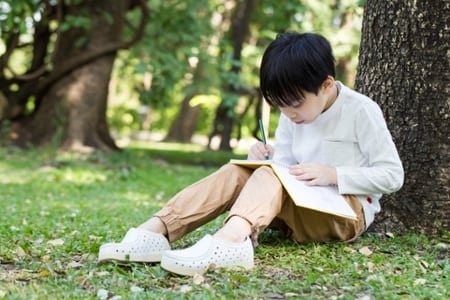 student sitting under a tree reading